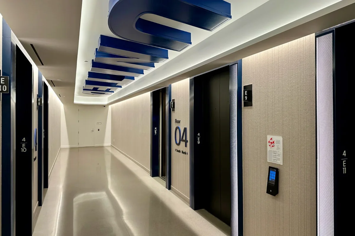 دکوراسیون سالن شرکت هواپیمایی با درب‌های مشکی و دیوارها و کف‌پوش کرمی و المان آبی روی سقف