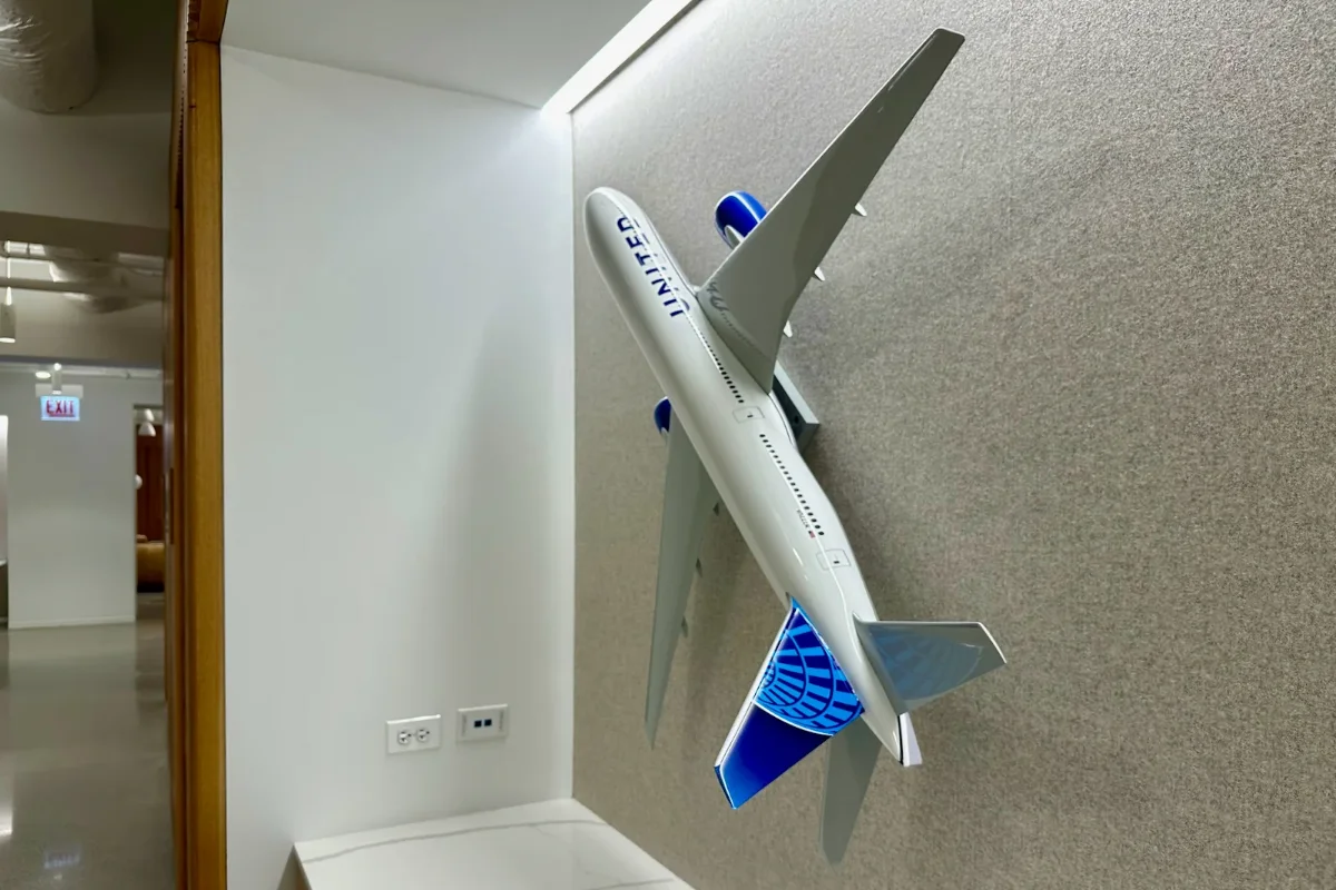 مجسمه هواپیما سفید آبی نصب شده روی دیوار نخودی شرکت هواپیمایی