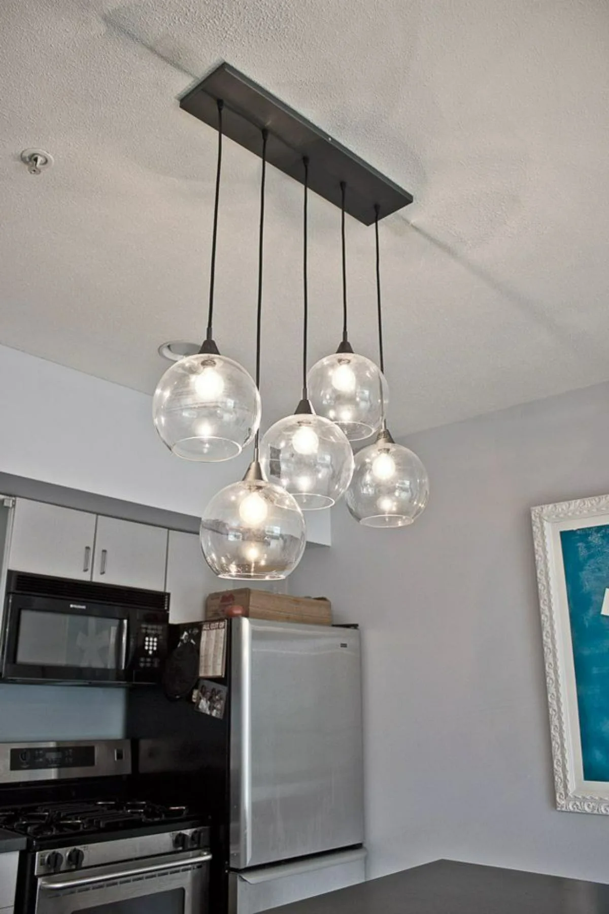 نورپردازی ترند سقف آشپزخانه با پنج چراغ آویزان گرد شیشه‌ای مدرن روی اپن