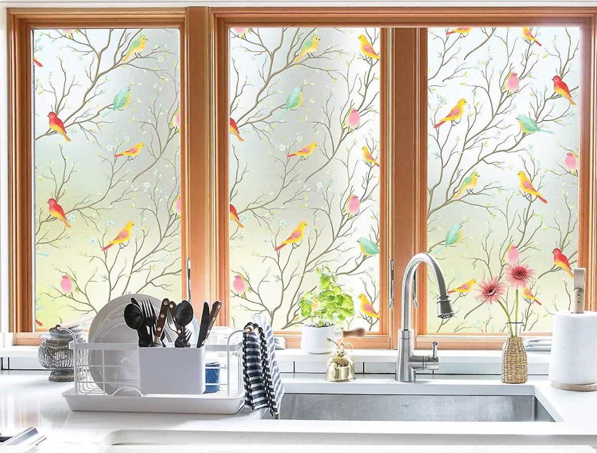 نصب برچسب با طرح شاخه و پرندگان رنگی روی پنجره آشپزخانه