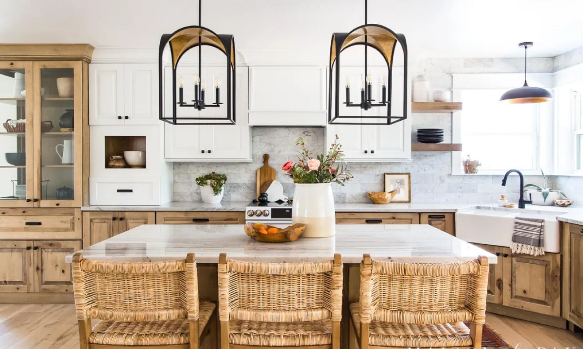 آشپزخانه با کابینت تمام چوب به رنگ طبیعی چوب و سفید با تزئینات صندلی‌های حصیری