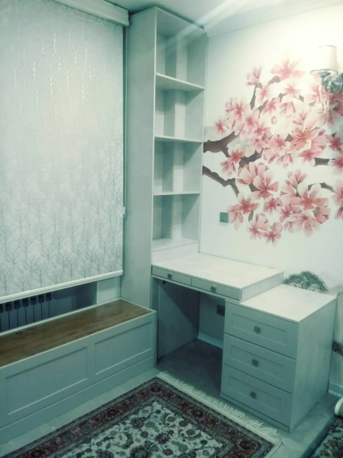 میز تحریر و کتابخانه سفید در اتاق با کاغذ دیواری طرح گل صورتی