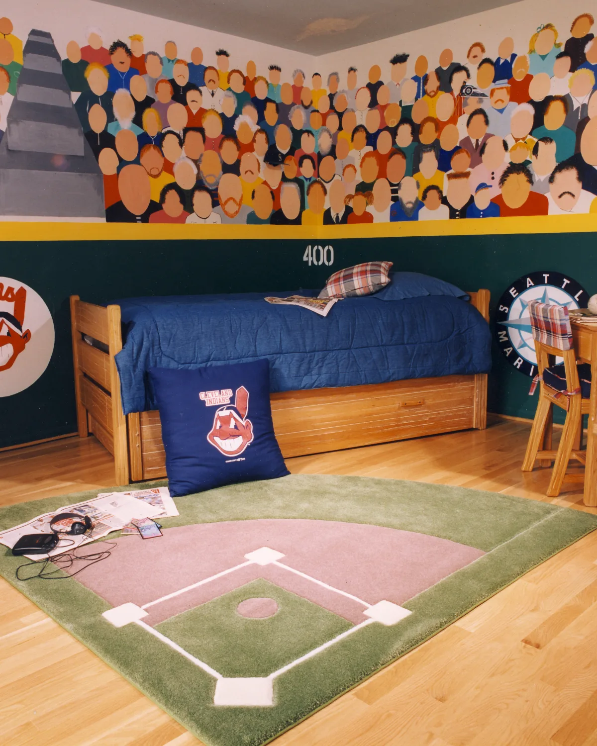 اتاق‌خواب پسرانه چوبی با روتختی آبی و فرش سبز رنگ به شکل زمین بیسبال